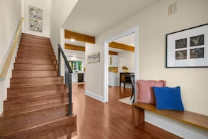 A wooden staircase leading to a kitchen area with a bench and cushions. - The Farmhouse | Mountain Views + Room to Roam (Port Angeles East)