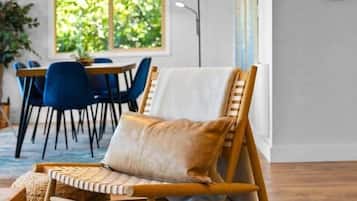 A room with a dining area, a hanging chair, a patterned rug, and a wall clock.