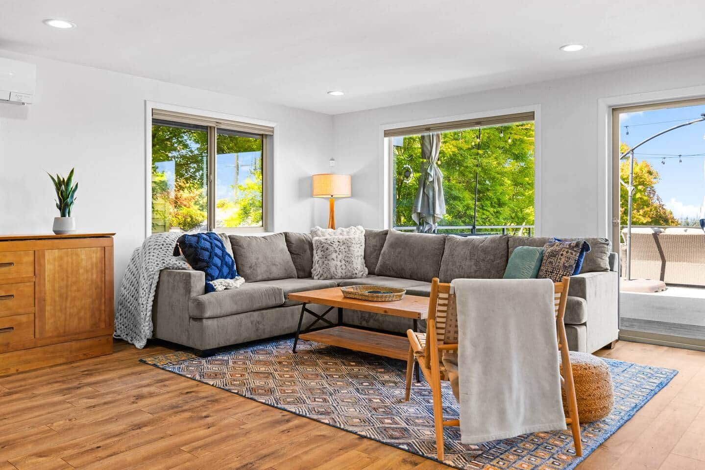 A modern living room with a sectional sofa, a wooden coffee table, and a patterned rug.