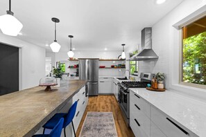 A modern kitchen with a central island, stainless steel appliances, and pendant lighting.