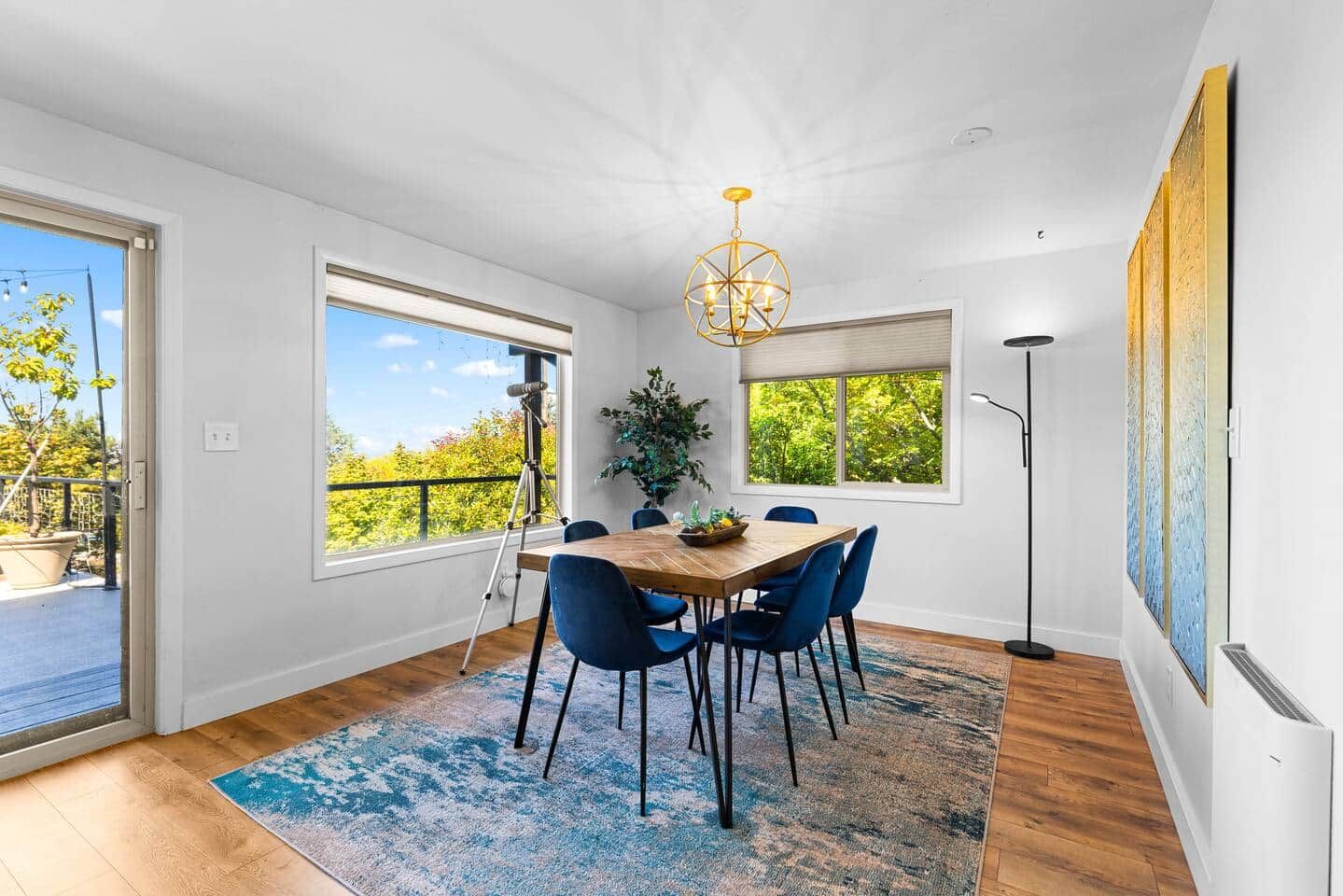 A dining area with a wooden table, blue chairs, and a chandelier.