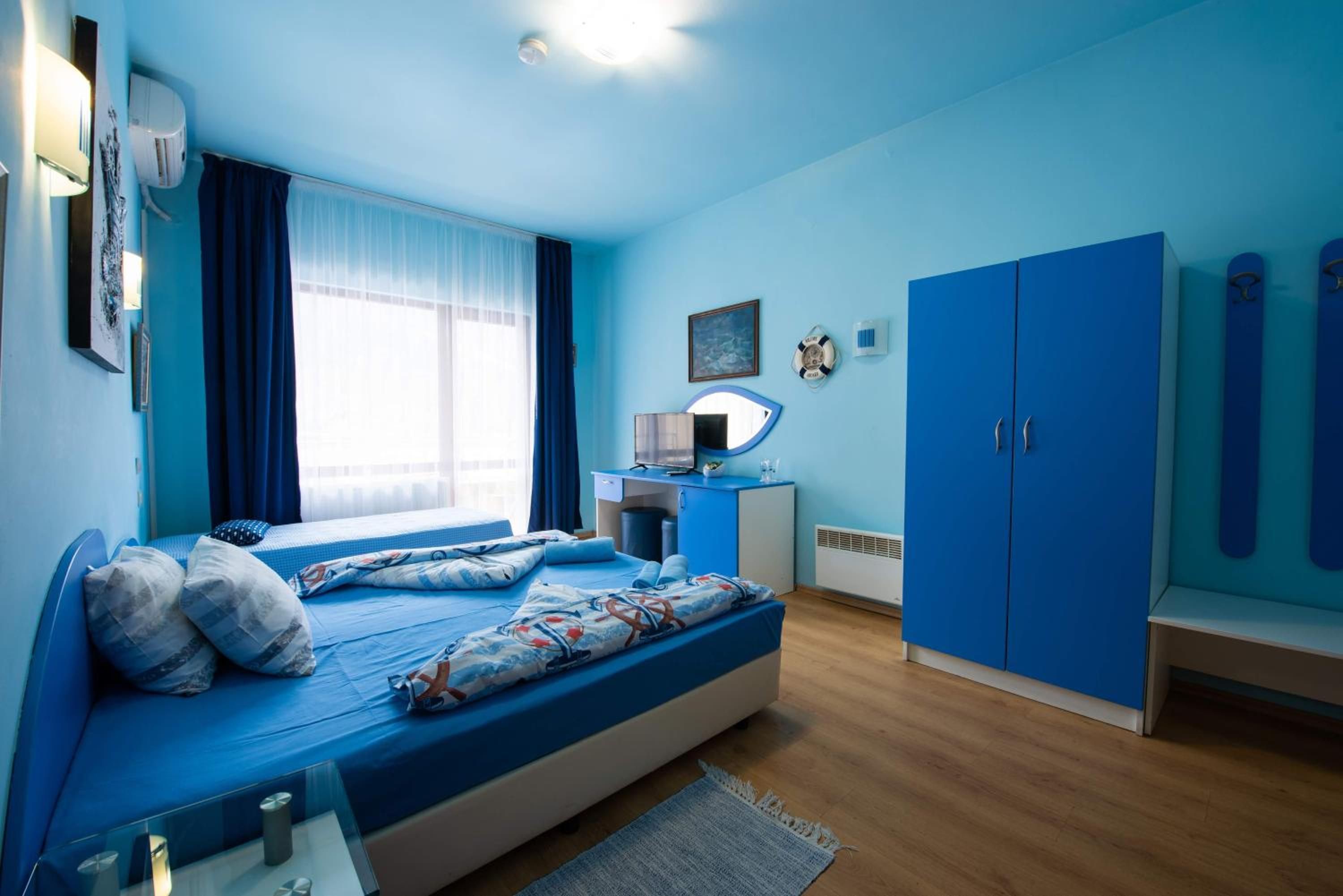 Un dormitorio con cama, escritorio, armario y ventana con cortinas.