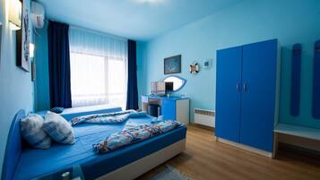 Un dormitorio con cama, escritorio, armario y ventana con cortinas.