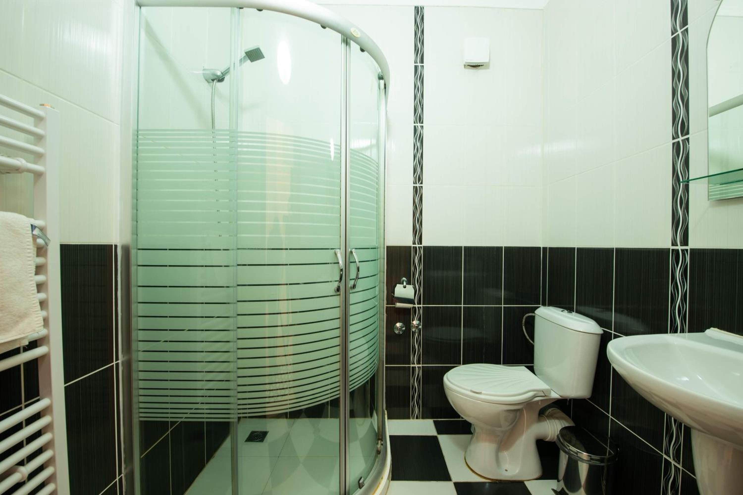A bathroom with a glass-enclosed shower, a toilet, and a sink.