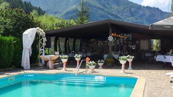 Un área de piscina con vistas a la montaña, mobiliario exterior y un bar.