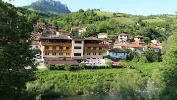Un pueblo en la ladera de una colina con casas tradicionales, un río y una montaña al fondo.