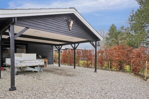 A covered outdoor area with a gravel floor, a truck, and a building in the background. - Lovely holiday home by Vellerup Vig (Skibby)