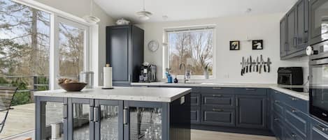 A modern kitchen with dark cabinetry, a large island, and a view of the outdoors.