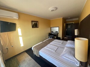 Una habitación de hotel con una cama, un escritorio, un televisor y una lámpara.
