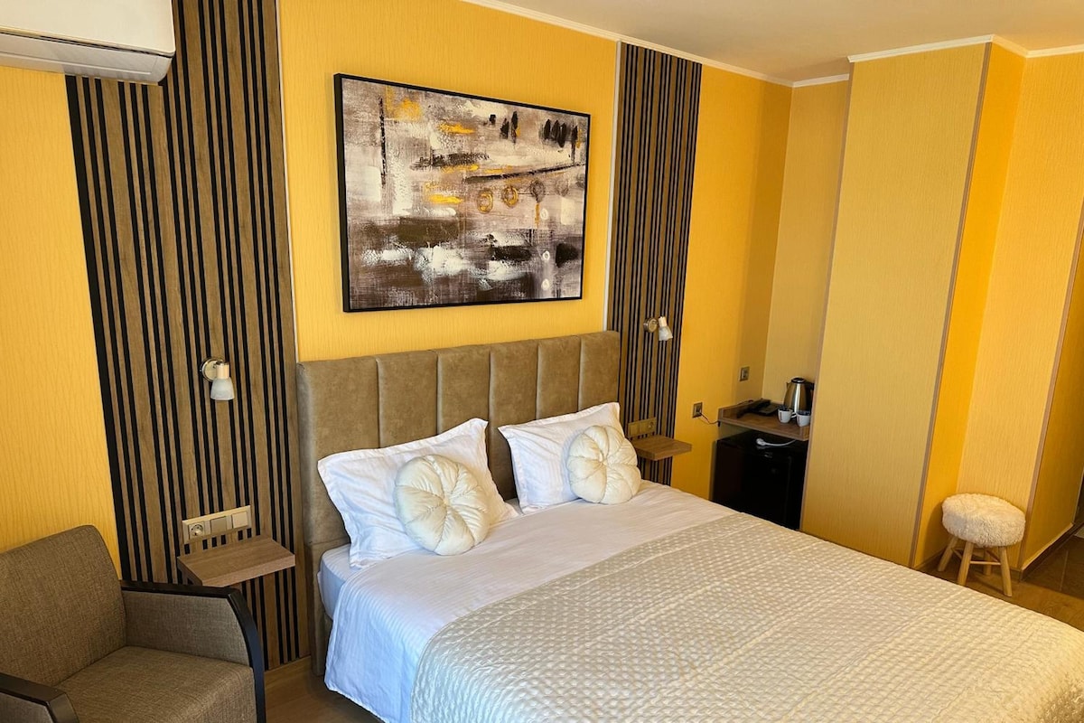 Habitación de hotel con cama, una silla, un escritorio, un cuadro en la pared y un panel decorativo a rayas.