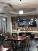 Un interior de restaurante con un letrero a cuadros, mesas, sillas y una pared decorada.