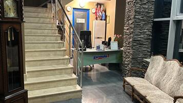 Un área de recepción con escalera, mostrador, sofá y un reloj.