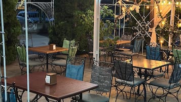 An outdoor patio area with tables and chairs, string lights, and a covered seating area.