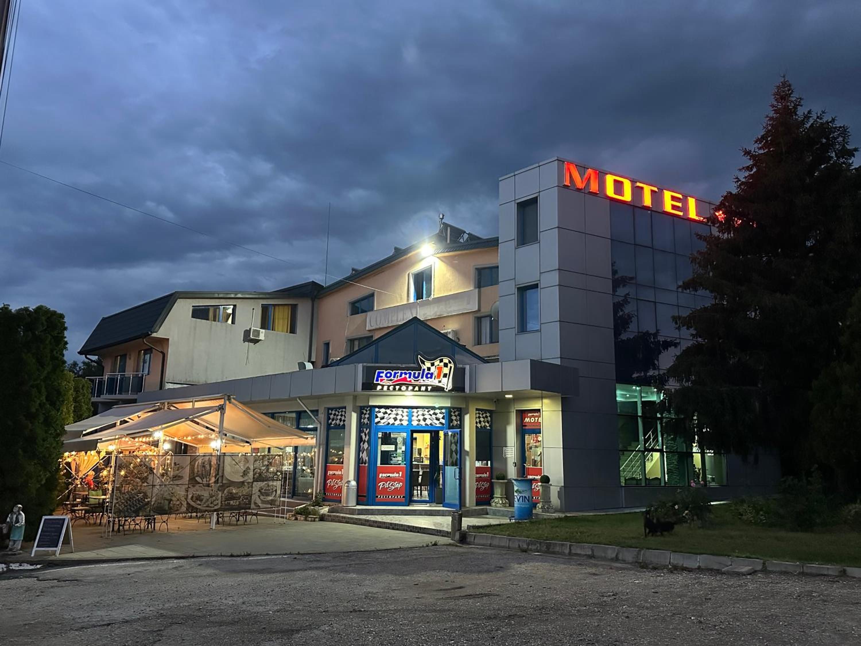 A motel with a prominent sign, a restaurant named 'Formula 1' with a racing theme, and a parking area.