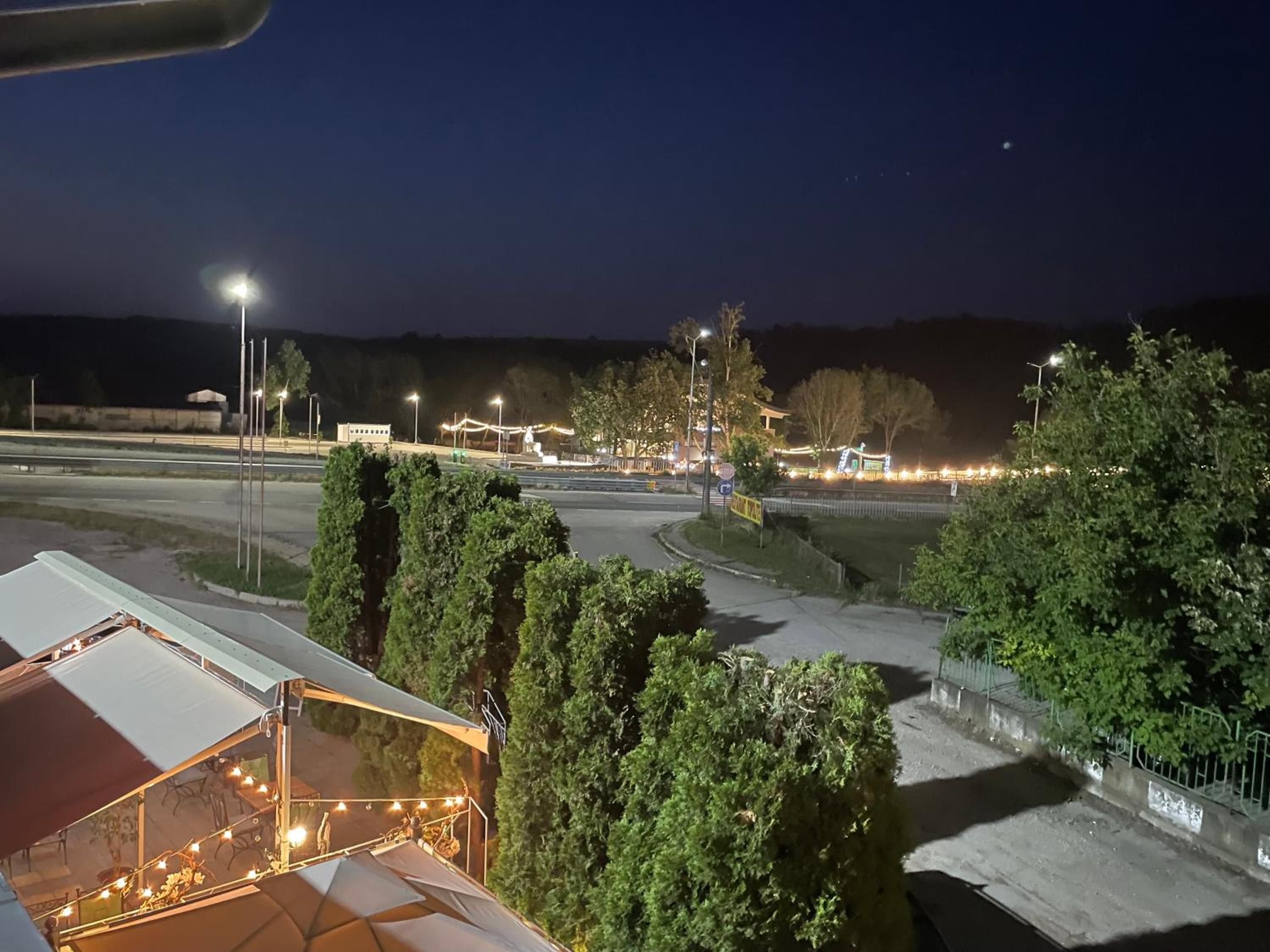 A nighttime view of a parking area with trees and street lamps.