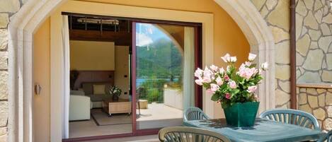 Un vano de piedra con puerta que da a una habitación con cama y vistas de un paisaje montañoso.