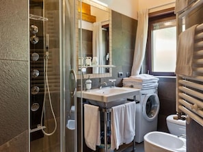A modern bathroom with a glass-enclosed shower, a sink with a mirror, a toilet, and a bathtub. - Tassido Coda Resort (Villalago)