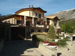 A two-story building with a stone facade, multiple balconies, and a mountain backdrop. - Tassido Coda Resort (Villalago)