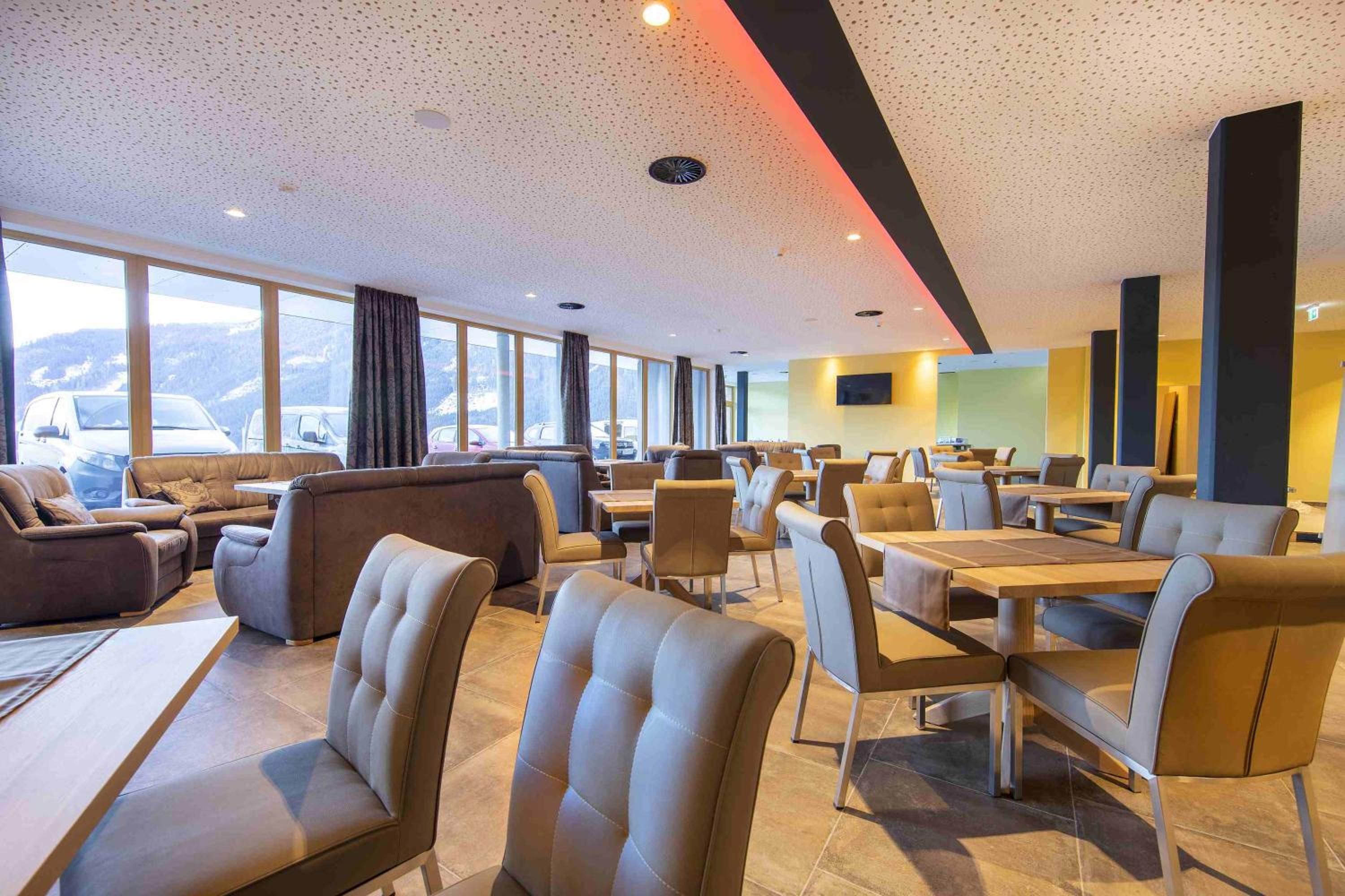Een moderne hotellobby met lederen zitplaatsen, een groot raam met uitzicht op bergen en een eigentijds plafondontwerp.