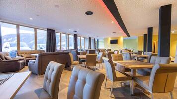 Een moderne hotellobby met lederen zitplaatsen, een groot raam met uitzicht op bergen en een eigentijds plafondontwerp.