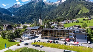 Un pueblo de montaña con un hotel destacado, una iglesia y un estacionamiento con automóviles.