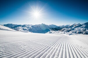A snow-covered mountain landscape with a clear sky and the sun shining brightly.