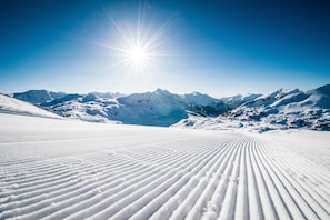 Paisaje nevado de montaña con cielo despejado y un sol brillante.