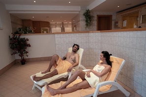 A room with two reclining chairs, a potted plant, and a tiled wall. - Apparthotel Samson (Tweng)