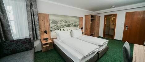 Habitación de hotel con cama, mesita de noche, armario y baño visible a través de una puerta abierta.