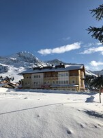 A multi-story building with a sign for 'Appart Hotel Samson' and 'Cafe Yvonnthe' in a snowy mountainous area.