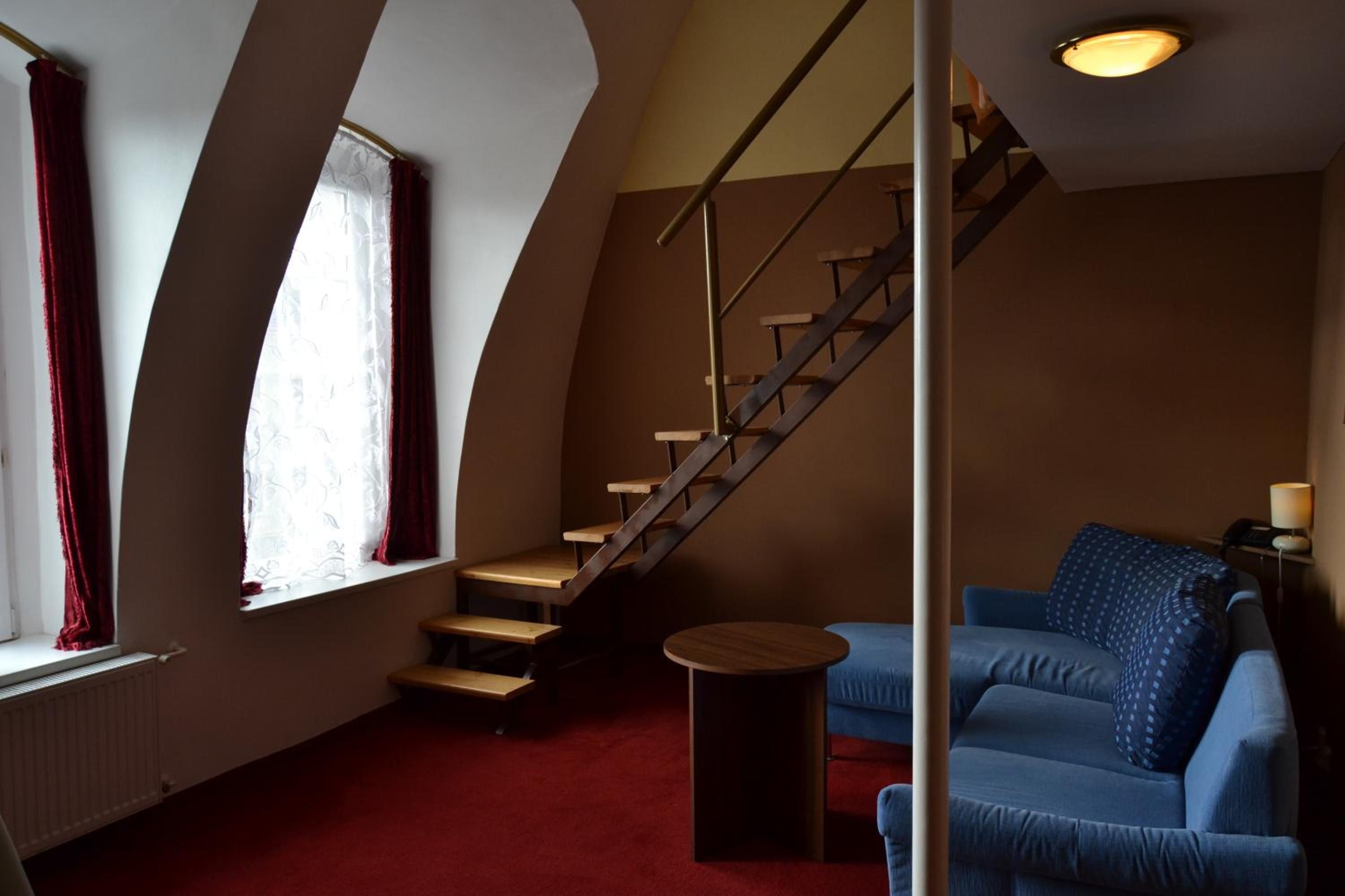 A room with a staircase, a blue sofa, and a small table.