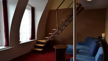 A room with a staircase, a blue sofa, and a small table.