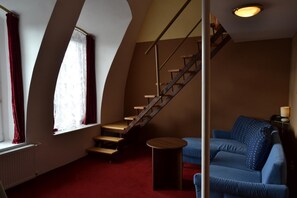 Une pièce avec un escalier, un canapé bleu et une petite table.
