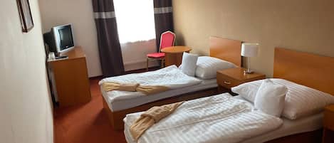 A hotel room with two beds, a desk with a television, a chair, and a window with curtains.