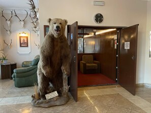 Une pièce comprenant une grande statue d  ’ours, une horloge et une porte donnant sur une autre pièce.