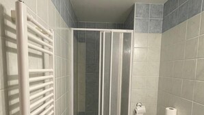 A bathroom with a shower enclosure, a toilet, a radiator, and a sink. - Hotel Aernvo Orel Oatec (Zatec)