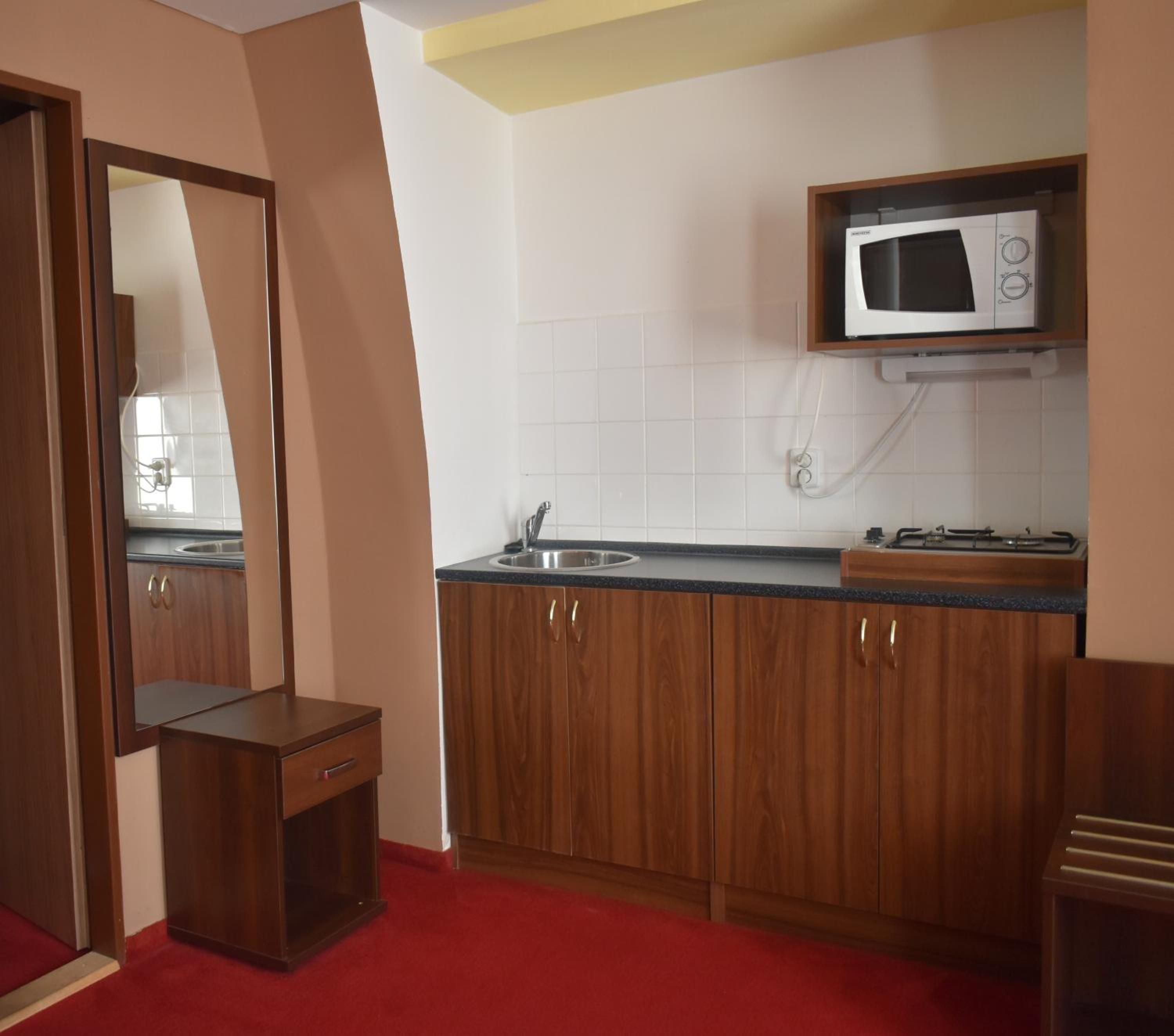 A compact kitchen with wooden cabinets, a microwave, and a sink.