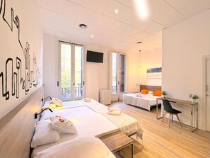 Habitación de hotel con dos camas, un escritorio y una televisión.