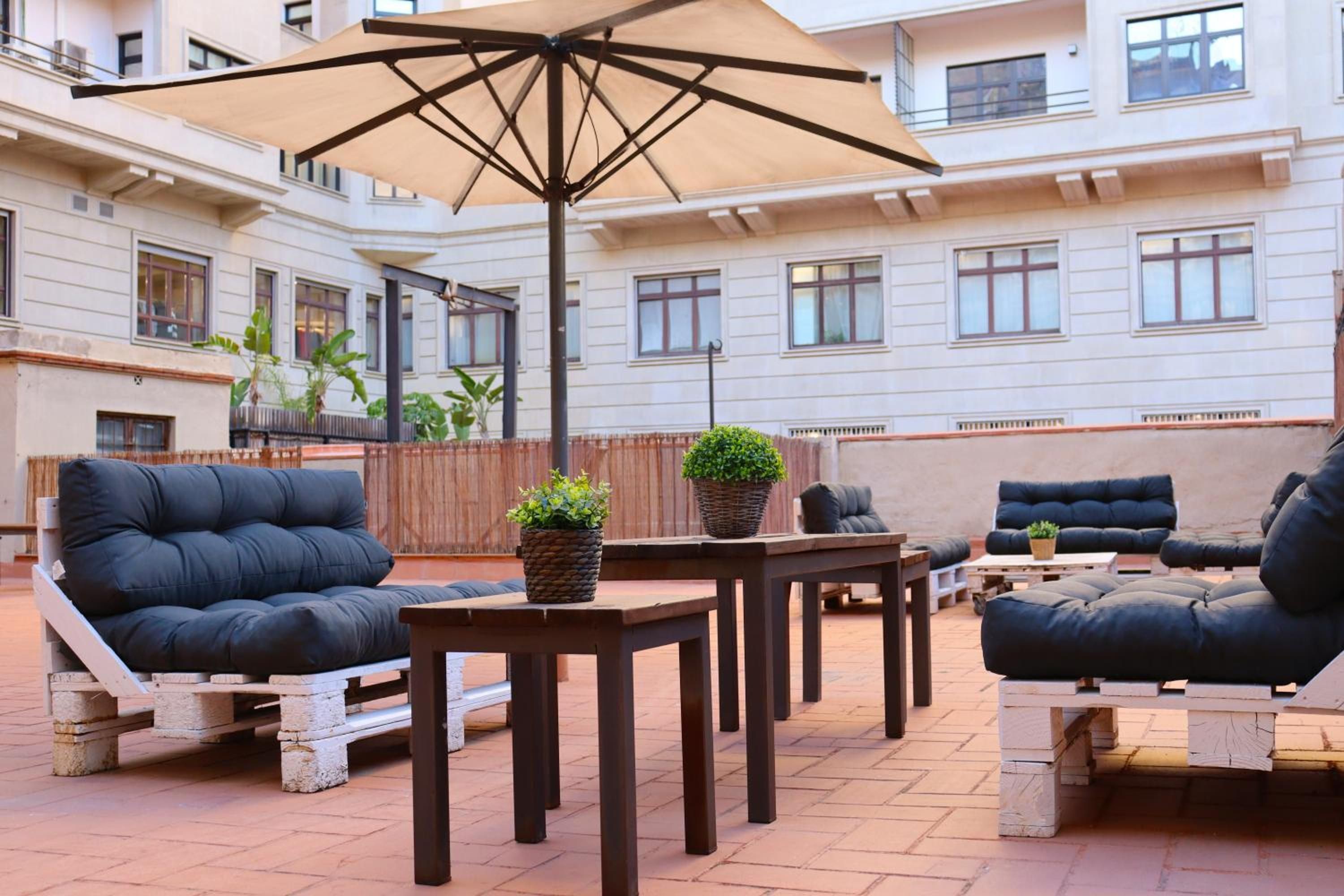 An outdoor patio area with a large umbrella, multiple seating options including sofas and chairs, and a potted plant.