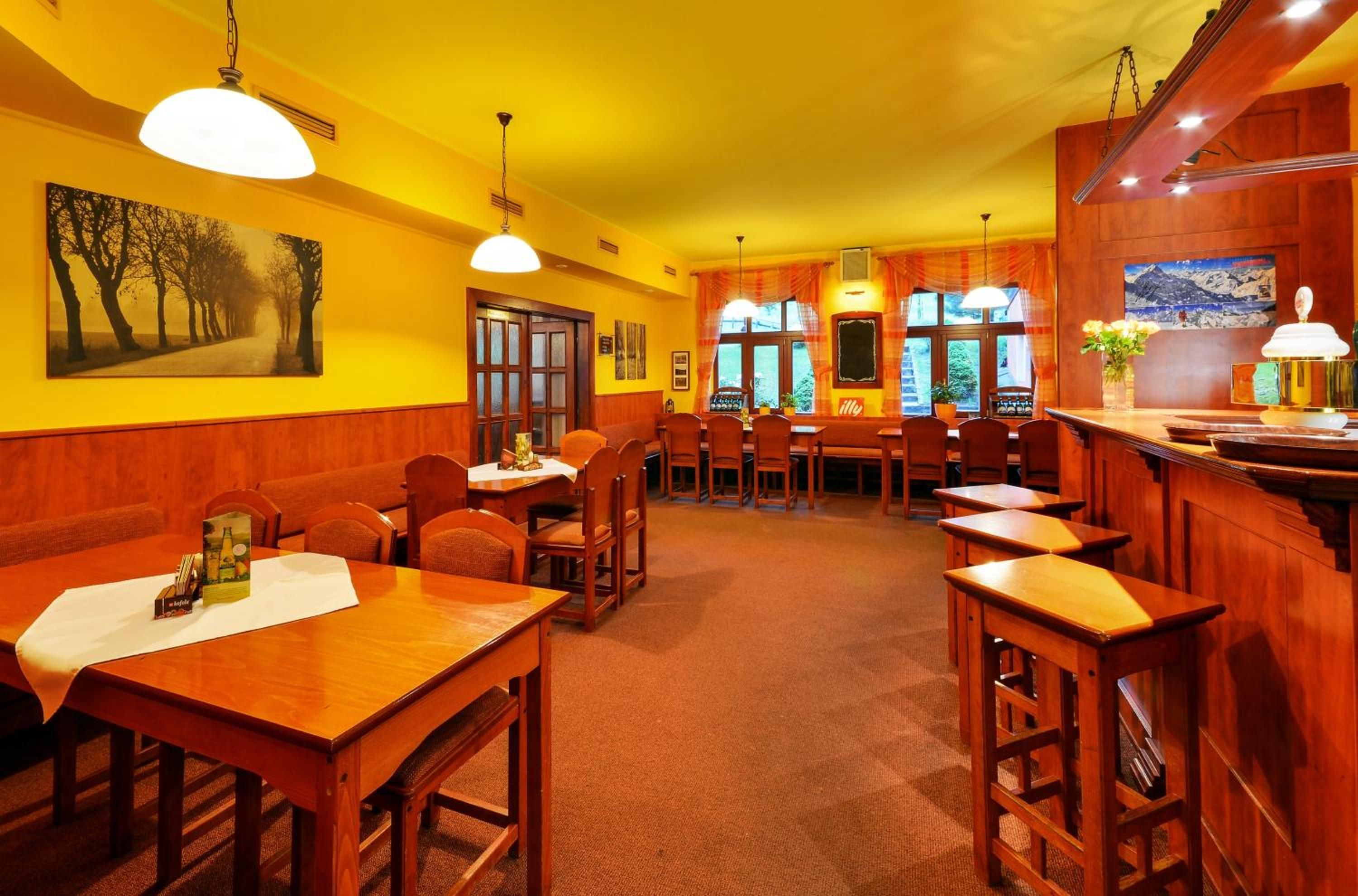 Un restaurante con mobiliario de madera, paredes amarillas y un ventanal grande.