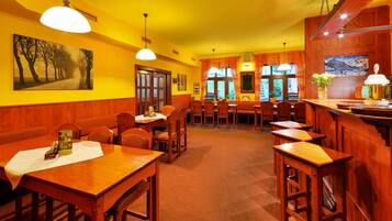 Un restaurante con mobiliario de madera, paredes amarillas y un ventanal grande.