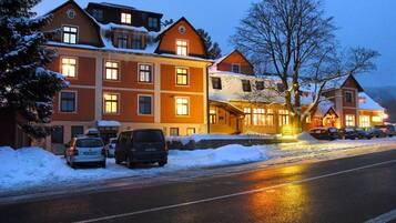 Ein Hotel mit mehreren Etagen, schneebedeckten Dächern und einem Parkplatz mit Autos.