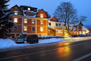 Un hotel de varios pisos, techos cubiertos de nieve y un estacionamiento con coches.
