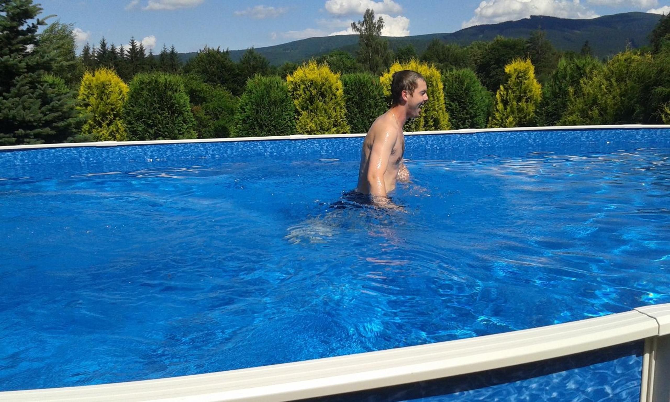 A person standing in a swimming pool with a view of trees and mountains in the background.