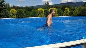 A person standing in a swimming pool with a view of trees and mountains in the background. - Hotel Stara Posta (Bela pod Pradedem)