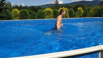 A person standing in a swimming pool with a view of trees and mountains in the background.