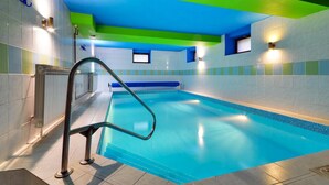 A swimming pool with a blue interior, surrounded by walls with a green and blue color scheme, and a metal ladder leading into the pool. - Hotel Stara Posta (Bela pod Pradedem)