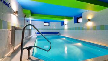 A swimming pool with a blue interior, surrounded by walls with a green and blue color scheme, and a metal ladder leading into the pool.