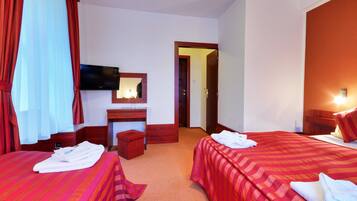 Habitación de hotel con dos camas, televisión, escritorio con espejo y puerta de baño.