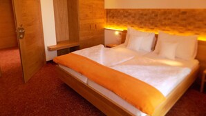 A hotel room with a large bed, wooden wardrobe, and a bench. - Mostlandhof (Purgstall an der Erlauf)